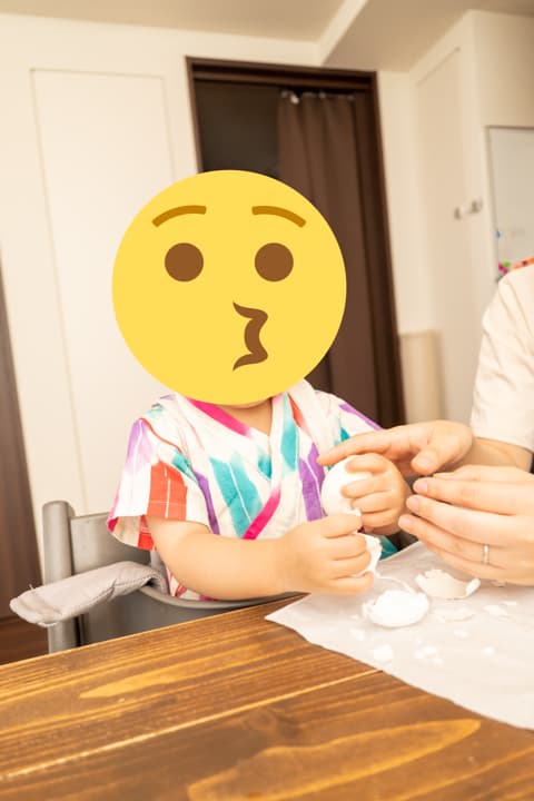 子供がゆでたまごの殻むきに挑戦している様子